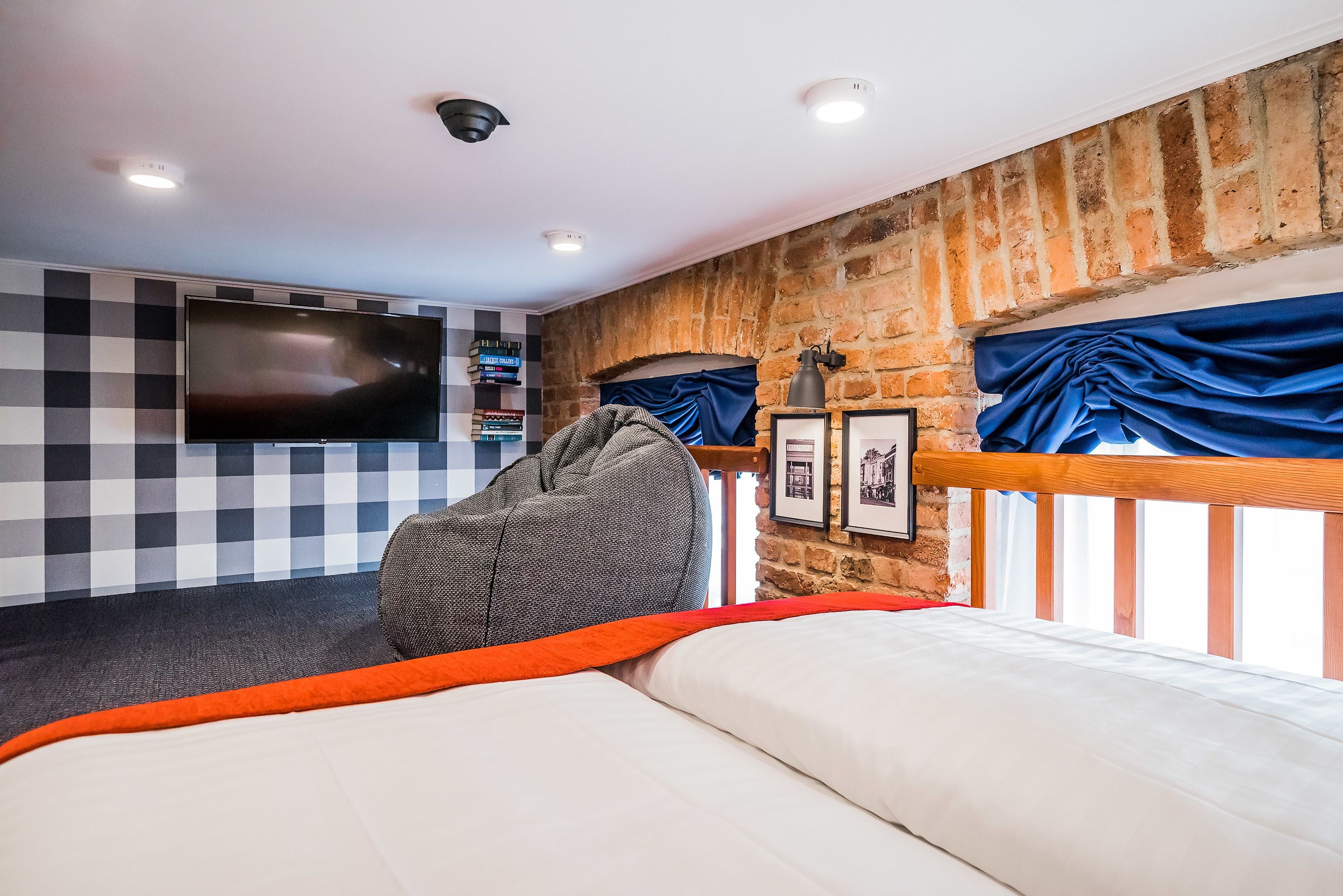 Une chambre à coucher avec un lit, une télévision, une bibliothèque et un mur en briques.