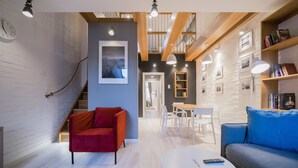 A modern living room with a red sofa, a blue sofa, a white coffee table, and a staircase leading to an upper level.