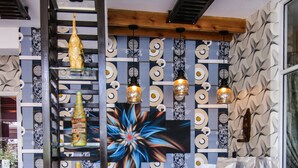 Un interior moderno con un muro decorativo, una estantería metálica con botellas y una encimera con bolsas.