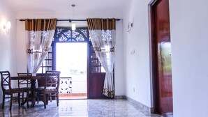 Una habitación con ventilador de techo, una mesa de comedor con sillas, suelo de baldosas y una puerta.