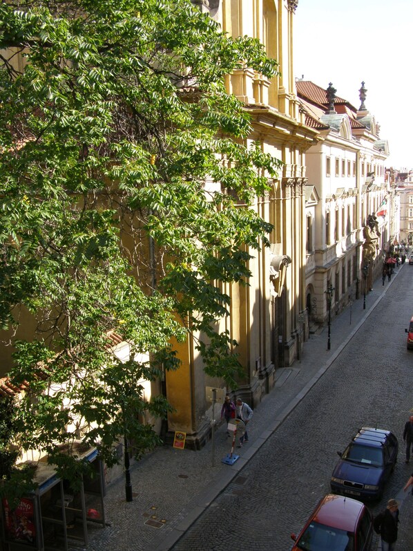 A cobblestone street lined with historic buildings, a tree in the foreground, and pedestrians. - Hostel Little Quarter (Prague)