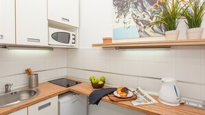 Eine moderne Küche mit weißen Schränken, einer Holzarbeitsplatte, einer Mikrowelle, einem Wasserkocher und einer Fruchtschale.