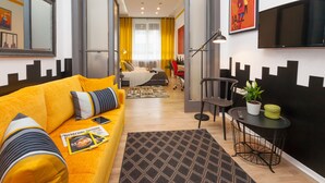 Ein modernes Wohnzimmer mit einem gelben Sofa, einem Couchtisch und einem Essbereich mit einem Stuhl und einer Pflanze.