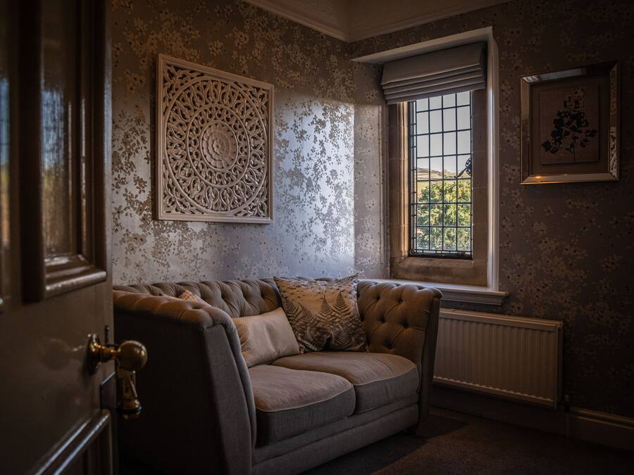 Una habitación de diseño clásico con un sofá capitonado, un panel decorativo en la pared, una ventana con rejas y un radiador.