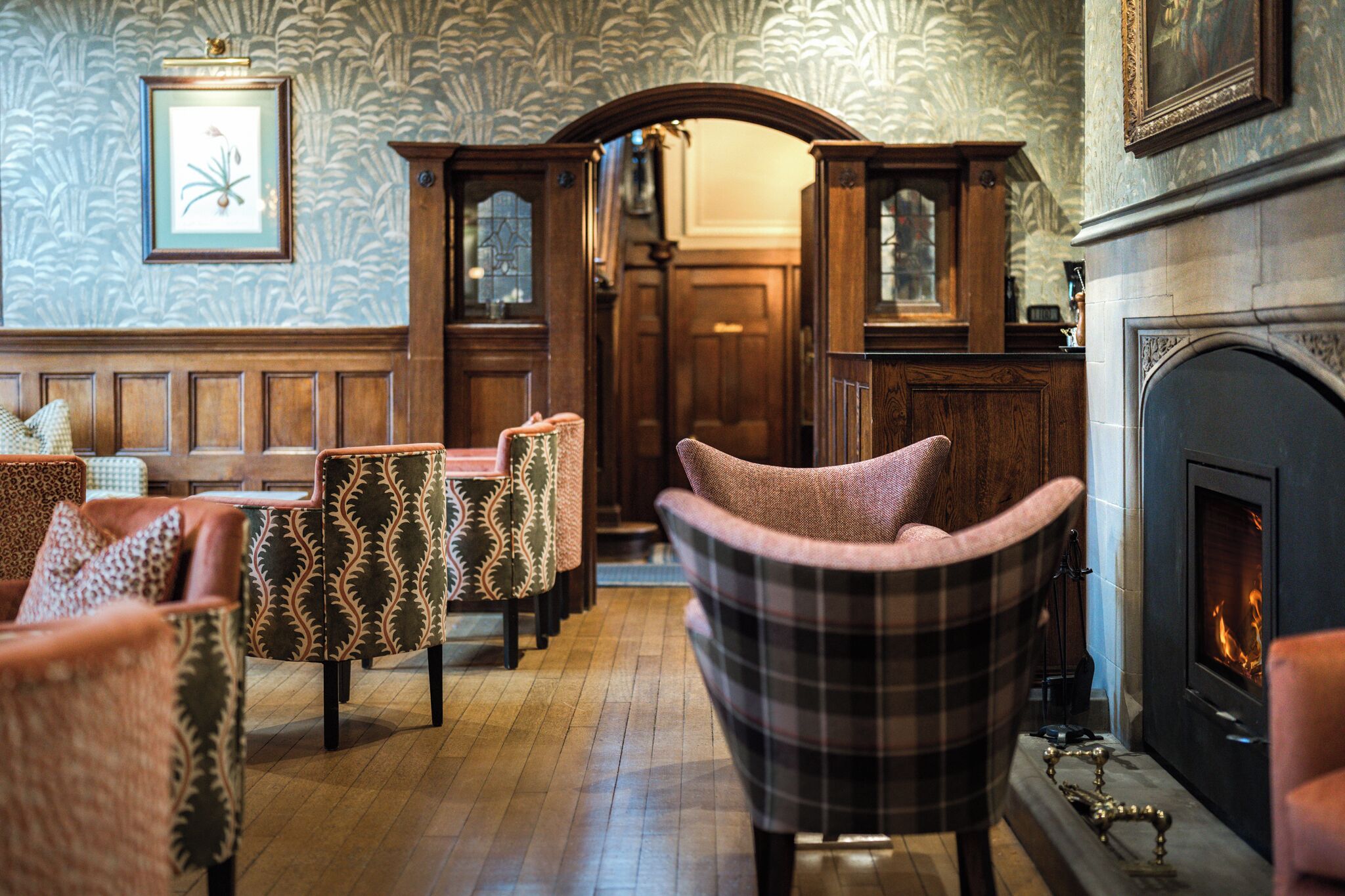 A room with wooden furniture, a fireplace, and patterned wallpaper.