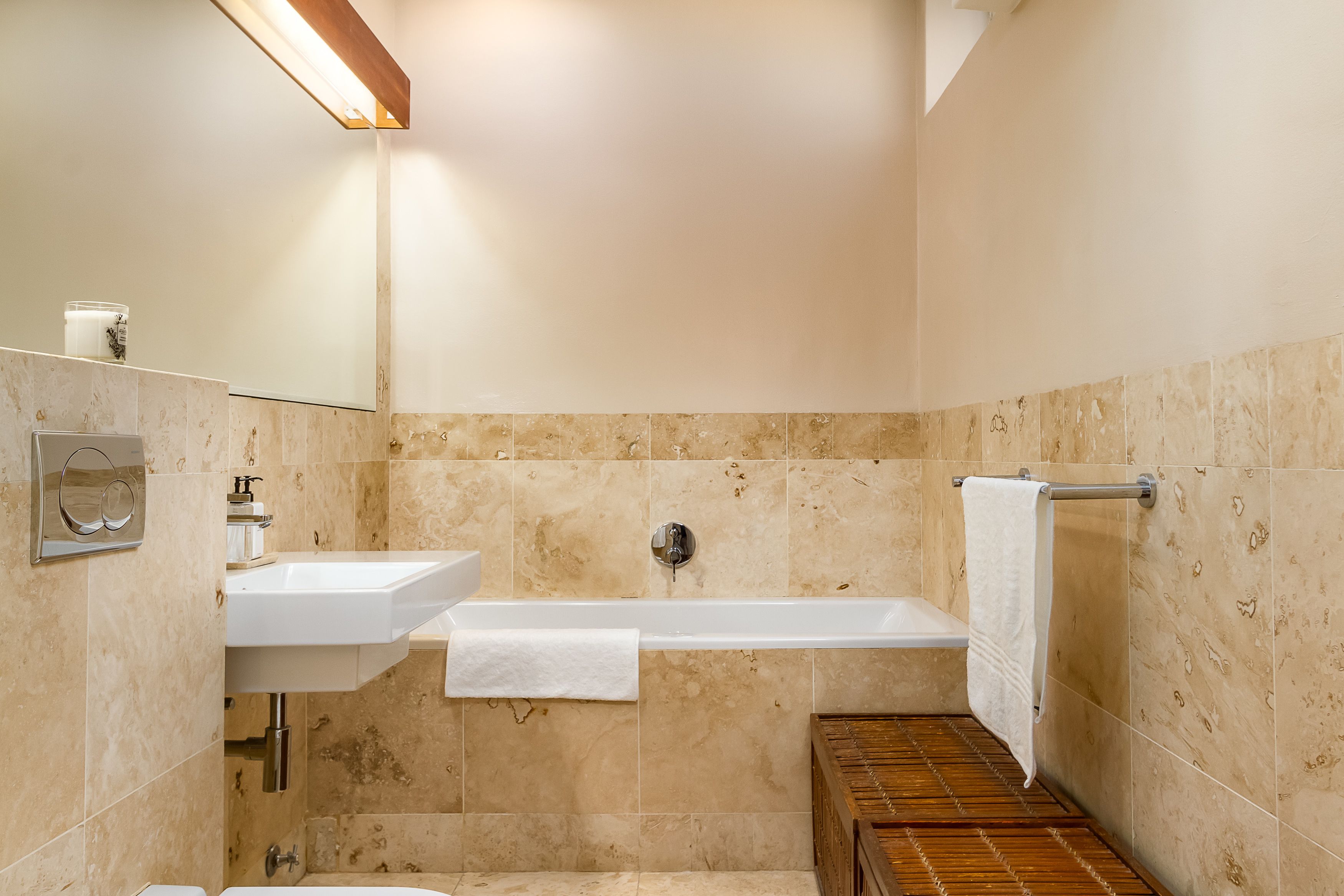 A bathroom with a sink, mirror, and bathtub.