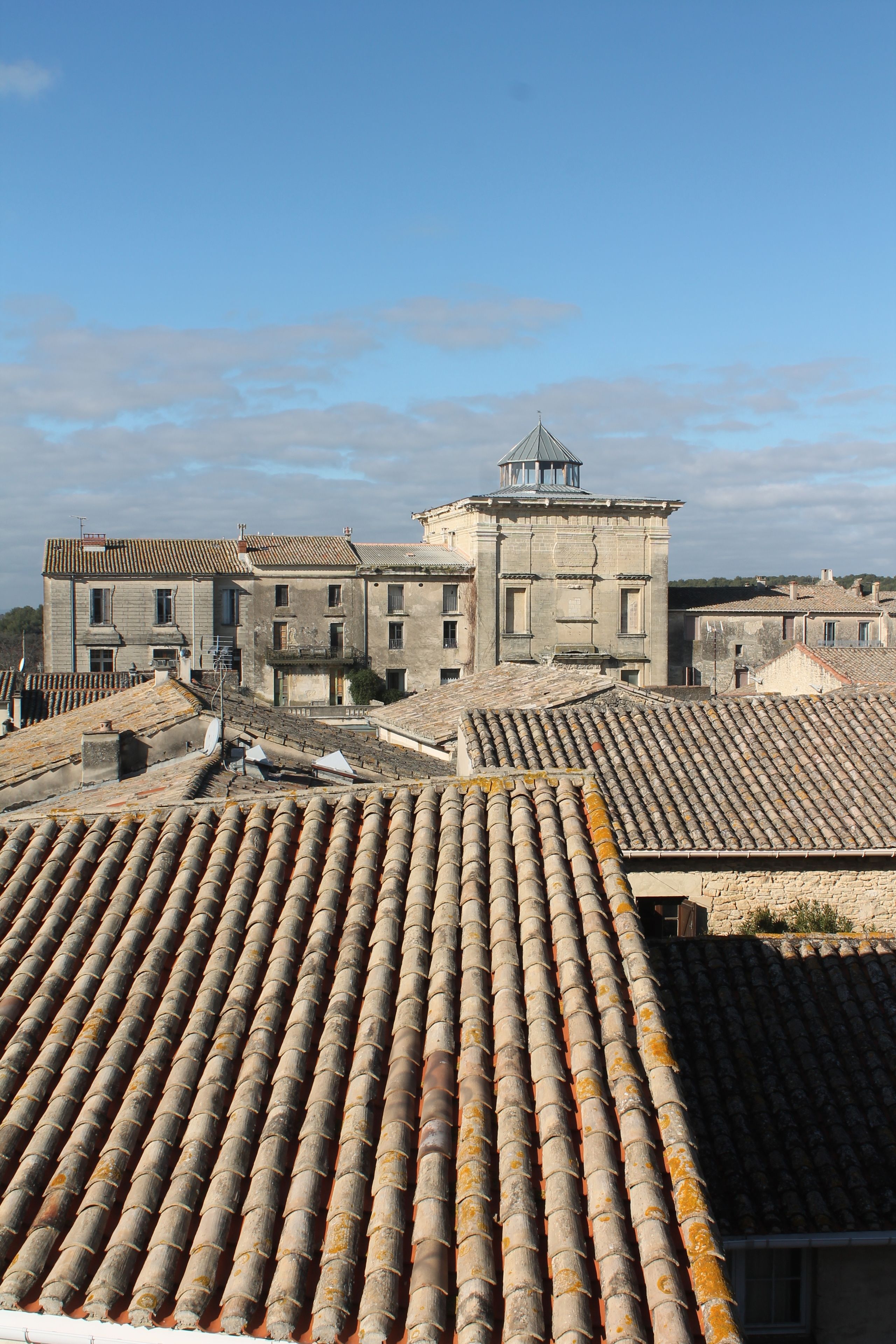 A view of a historic building with a prominent tower and a tiled roof.