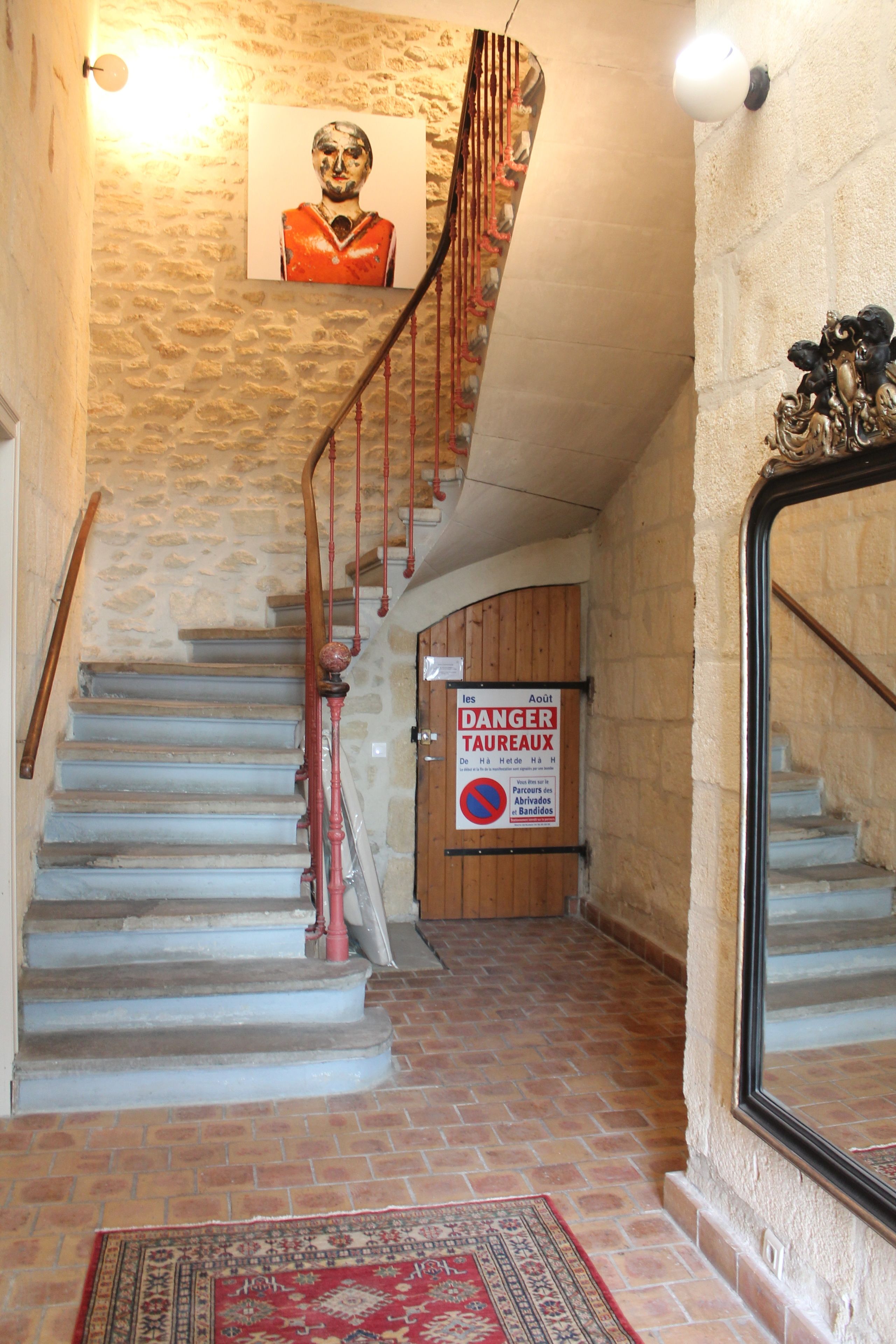 A staircase with a red handrail, a warning sign, and a patterned rug on the floor.