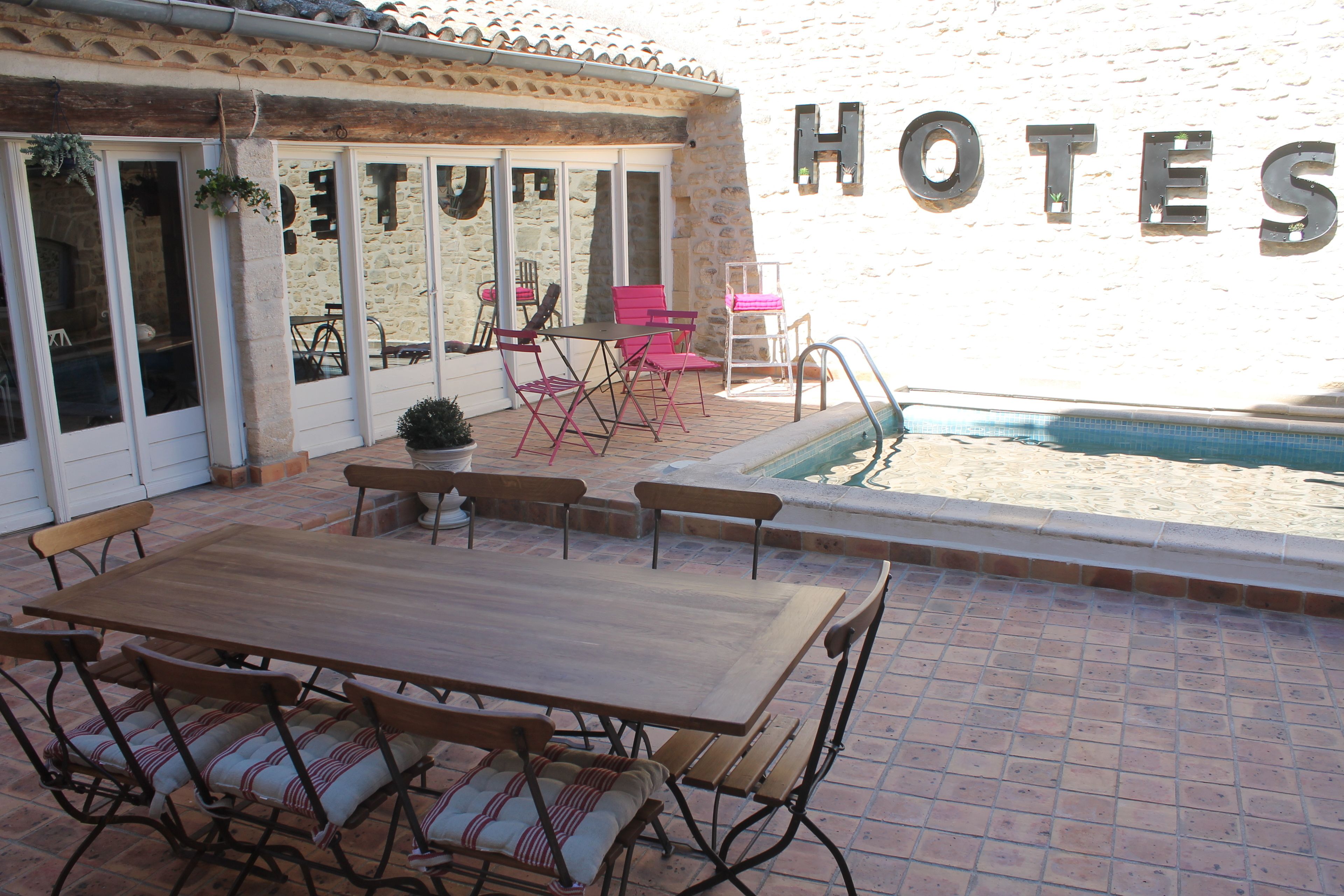 Ein Terrassenbereich mit Holztisch und -stühlen, einem Pool und einem Schild mit der Aufschrift 'HOTELS'.