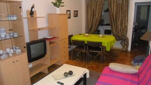 Un espacio habitable compacto con televisor, mesa de comedor y sofá.
