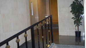 Una escalera de mármol con barandilla negra y dorada que conduce a una puerta de madera.