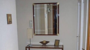 Un pasillo con piso de madera, una consola con espejo encima y una puerta a la derecha.
