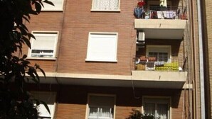 Un edificio residencial de varios pisos con balcones, ventanas y una entrada visible a nivel de calle.
