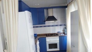Eine kleine Küche mit blauen Schränken, einem weißen Kühlschrank und einem Herd.