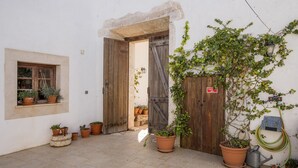 A courtyard with potted plants, a wooden door, and a window with plants. - F - Casa do Vigia in Quinta das Alagoas by DreamAlgarve (Lagos)