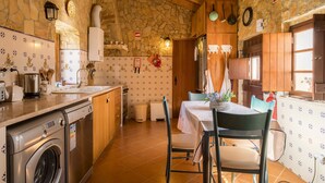 A kitchen with a washing machine, a sink, a stove, and a dining area with a table and chairs. - F - Casa do Vigia in Quinta das Alagoas by DreamAlgarve (Lagos)