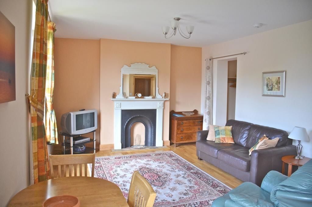 Una sala de estar con chimenea, televisión, sofá y mesa de comedor.