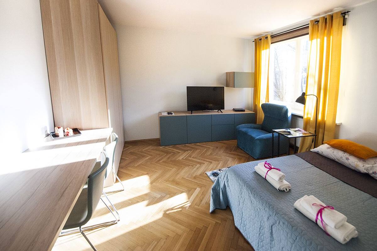 Ein Hotelzimmer mit Bett, Schreibtisch, Stuhl, Fernseher und einem Fenster mit Vorhängen.