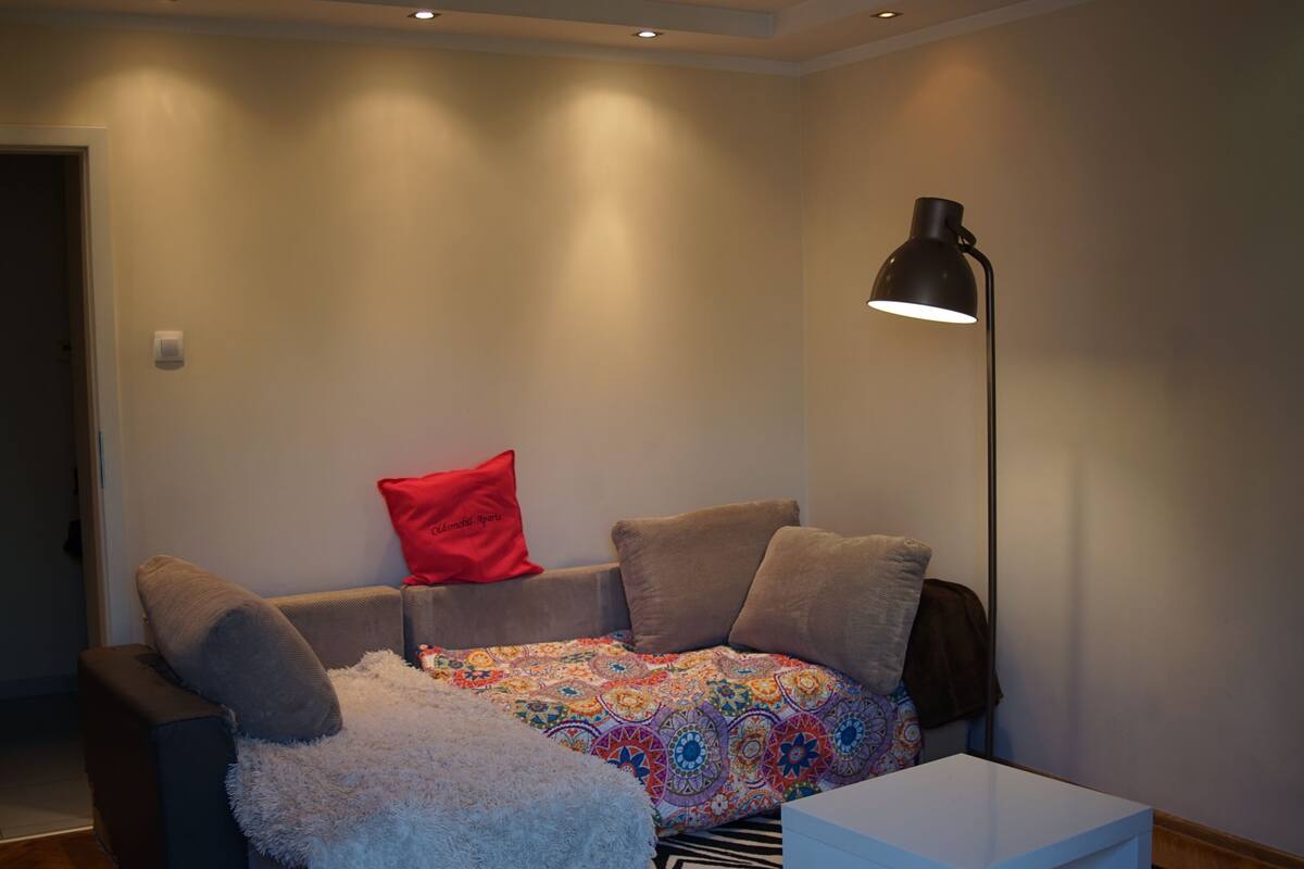 Ein gemütliches Wohnzimmer mit einer Couch, einer gemusterten Decke und einer Stehlampe.