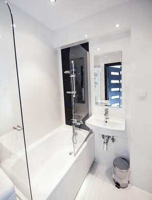 A modern bathroom with a glass-enclosed shower, a white sink, and a mirror above it. - Oldsmobil-Aparts (Kraków)
