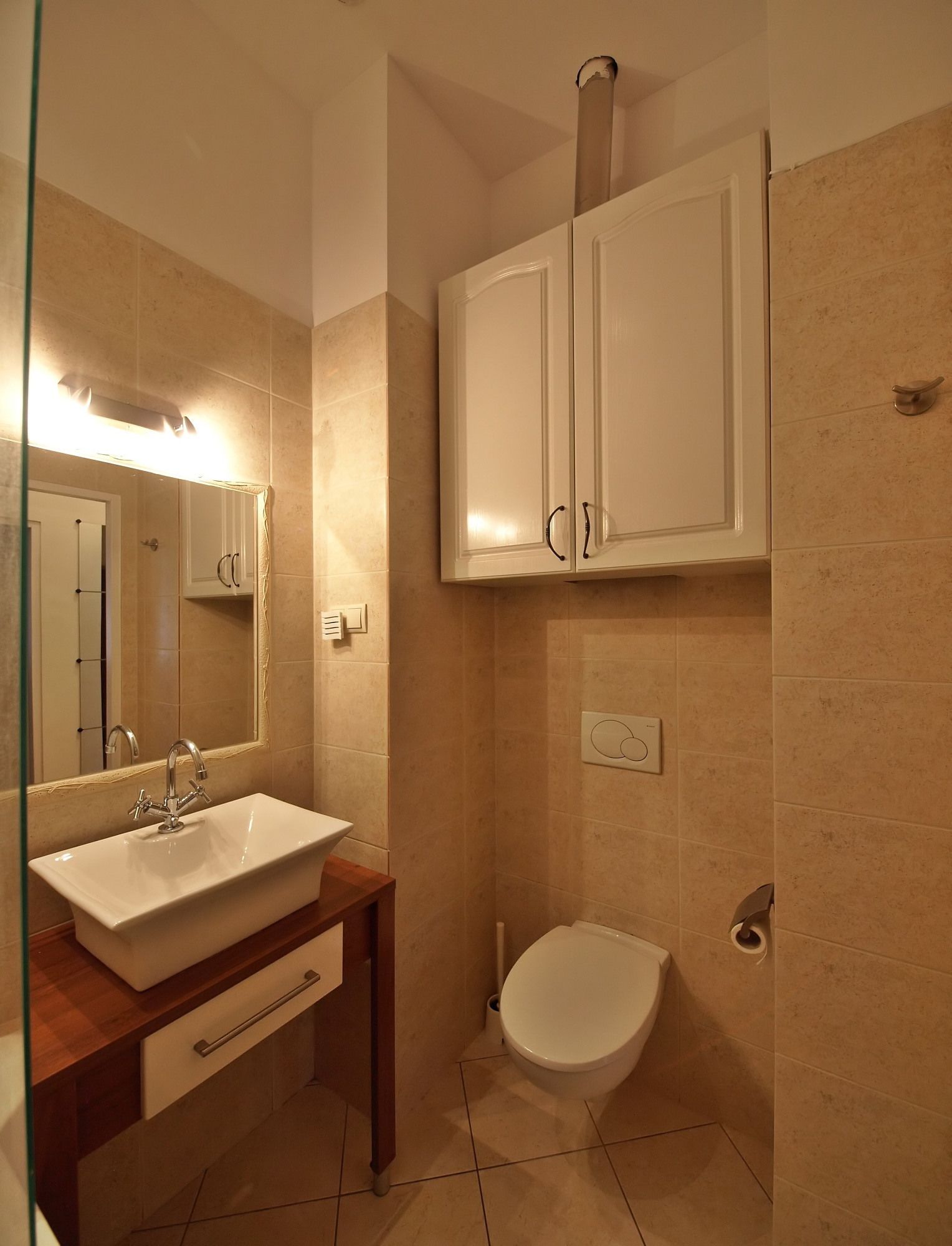 A bathroom with a sink, mirror, cabinet, toilet, and a towel rack.