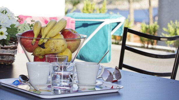 A table with a fruit bowl, two cups, and glasses of water. - Apartments Ragusa Palace- Dardin (Dubrovnik)
