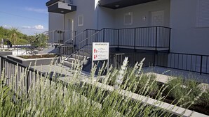 A modern apartment building with a sign indicating the direction to the parking area. - Apartments Ragusa Palace- Dardin (Dubrovnik)