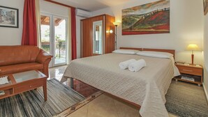 Ein Hotelzimmer mit einem Bett, einem Schlafsofa, einem Nachttisch, einer Lampe, einem Gemälde und einem Vorhangfenster.