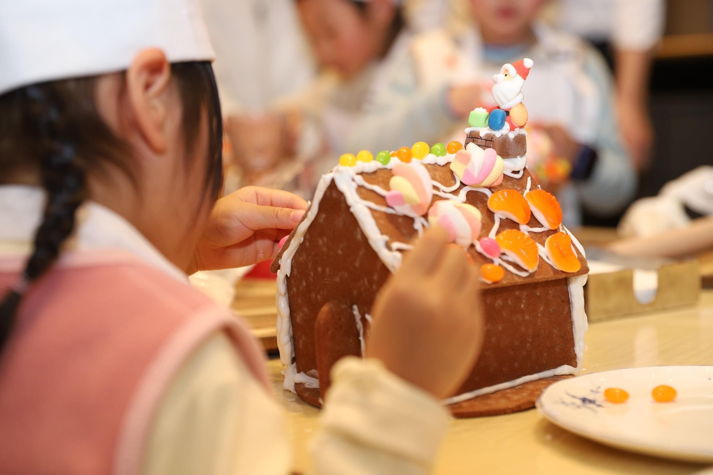 Una casa de jengibre con decoraciones coloridas y una figura de Santa Claus en la cima.