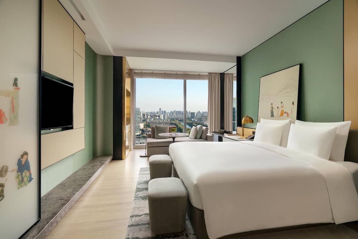 Una habitación de hotel moderna con una cama grande, un televisor de pantalla plana, un escritorio y vistas a la ciudad.