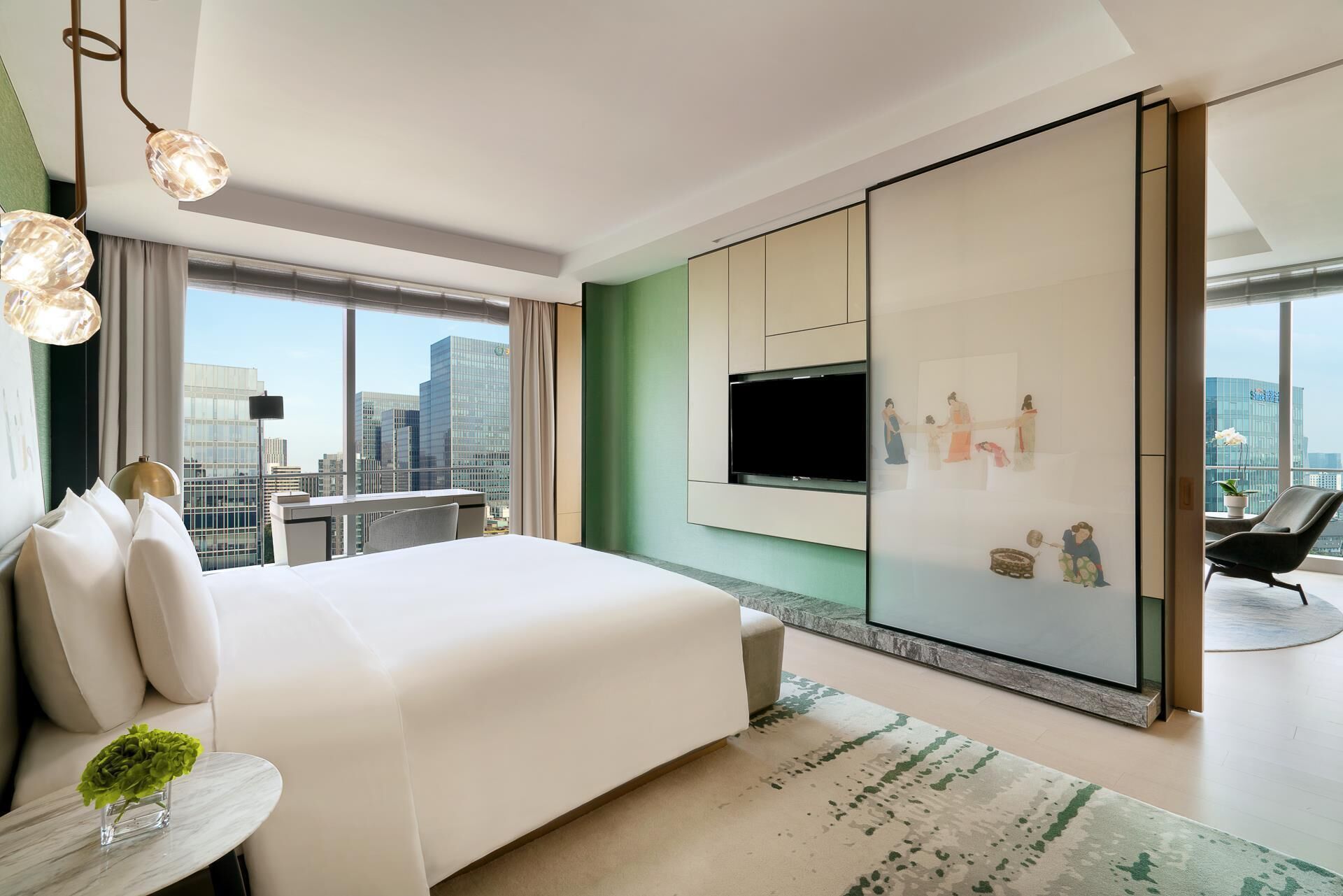 Una habitación de hotel moderna con una cama grande, un televisor montado en la pared y vistas a la ciudad.