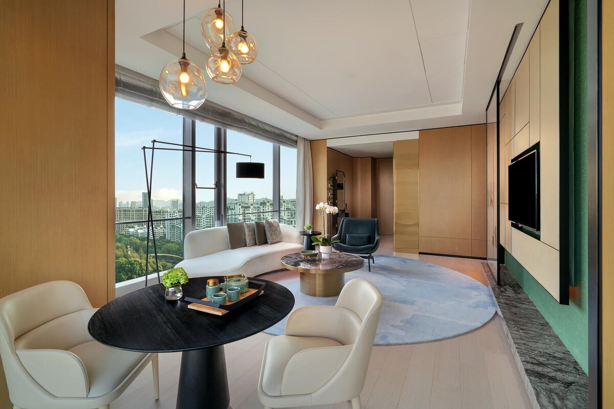 Un salon moderne comprenant un canapé, deux fauteuils, une table basse et un téléviseur.