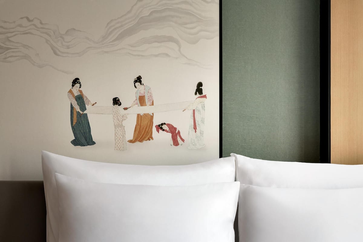Una pared con un mural que muestra cuatro figuras con vestimenta tradicional.