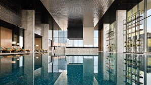 A modern indoor swimming pool with a clear blue water surface, large windows, and a minimalist design.
