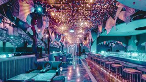 A modern bar area with seating and a ceiling adorned with hanging lights and decorative elements.