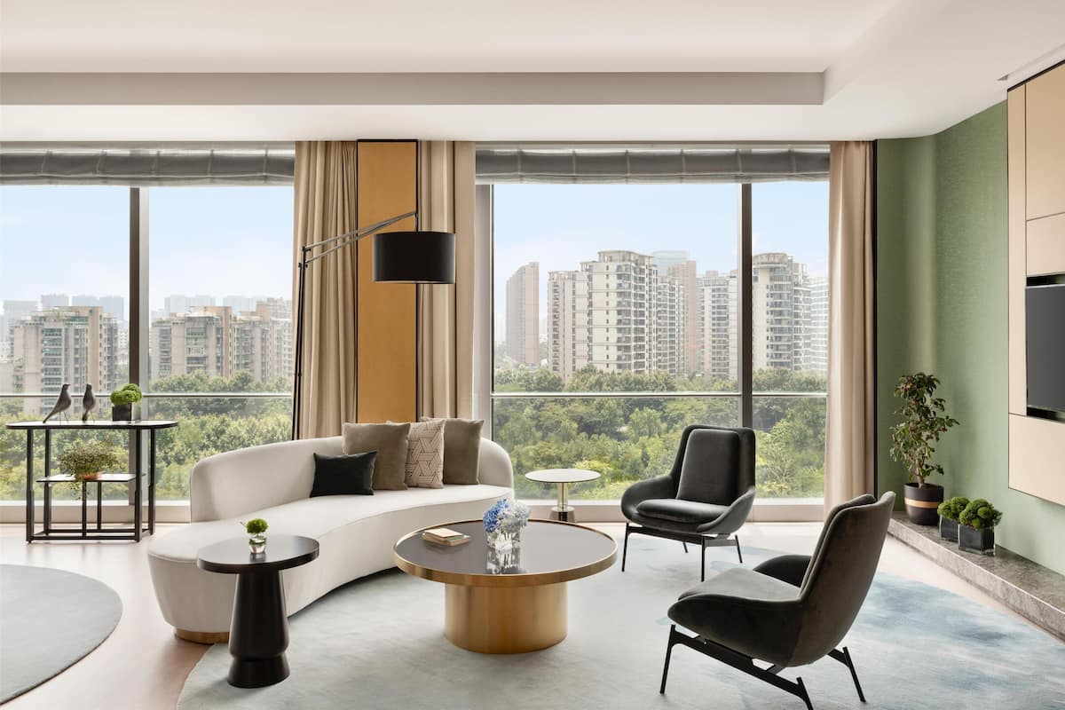 Una sala de estar moderna con un sofá, sillones, una mesa de centro y un televisor montado en la pared.