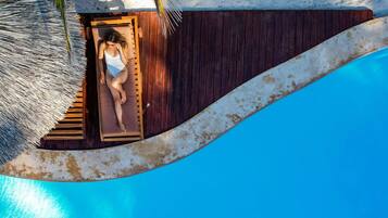 Una piscina al aire libre, sombrillas, sillones reclinables de piscina
