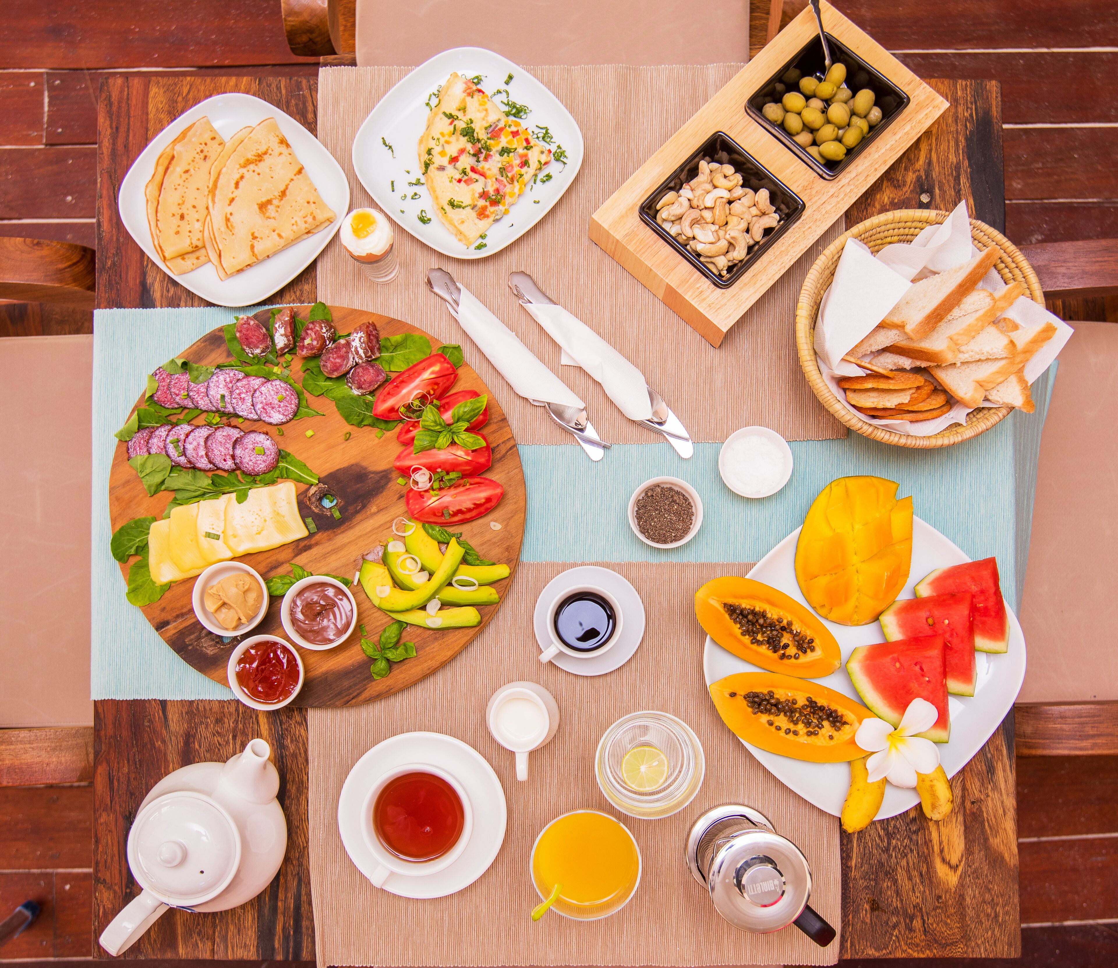 Un desayuno abundante con diversas comidas y bebidas sobre una mesa de madera.