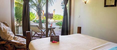 Habitación de hotel con una cama, una silla, una mesa y vistas al exterior.