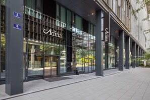 Un edificio moderno con ampie vetrate e il nome 'Adina' ben visibile.