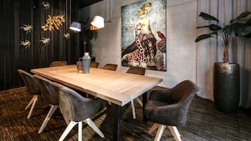 Un comedor moderno con una mesa de madera, sillas de cuero, un cuadro grande y una planta en maceta.