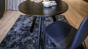 A modern hotel room with a bed, a round table with a chair, a coffee setup, and a ceiling light fixture. - Adina Serviced Apartments Vienna (Vienna)