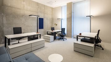 A modern office space with a large desk, office chairs, a sofa, and a small table.