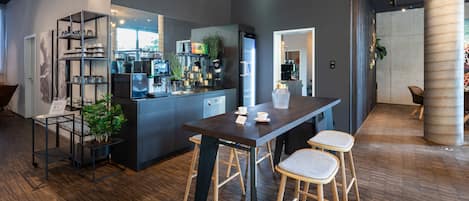 A modern kitchen with a central island, bar stools, and a coffee machine.