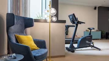Et moderne værelse med en blå lænestol, en gulvlampe og en motionscykel.