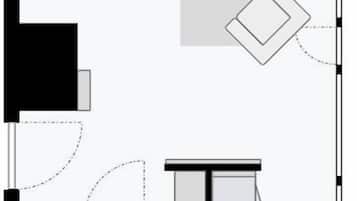 A floor plan of a hotel room with a bed, a desk, a chair, a small table, a sink, and a toilet.