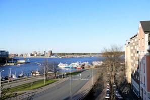 A view of a river with boats docked along the shore, a bridge in the background, and buildings adjacent to the riverbank.