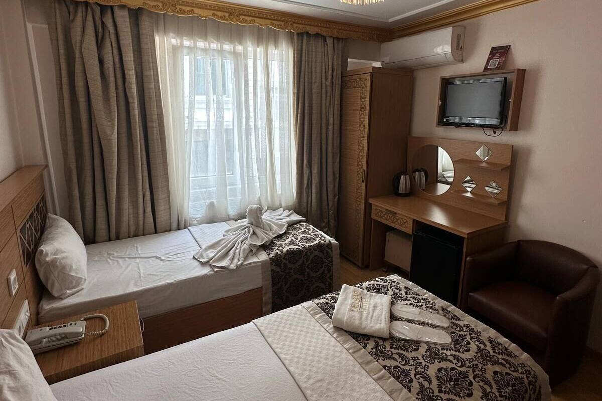A hotel room with two beds, a desk, a television, and a chair.