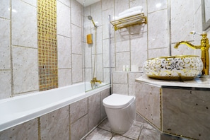 Un baño con una bañera blanca, un grifo dorado y un lavabo estampado.