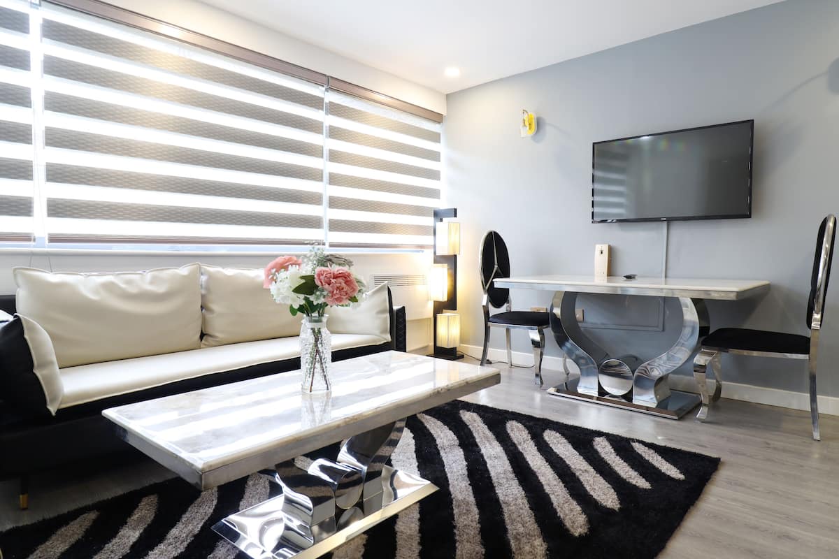 Uma sala de estar moderna com sofá, mesa de centro, TV e um espaço de jantar com cadeiras e mesa.